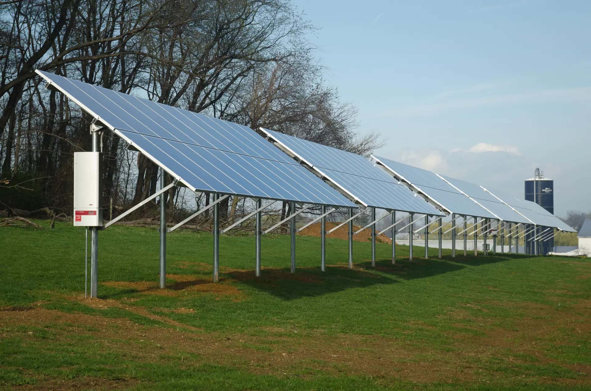 Bir tavuk çiftliğinin arazisine kurulmuş güneş enerjisi panelleri ve arka planda silo